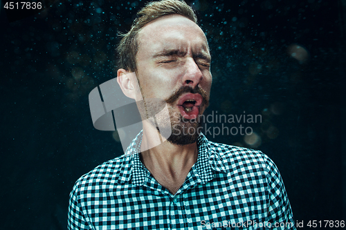 Image of Young handsome man with beard sneezing, studio portrait