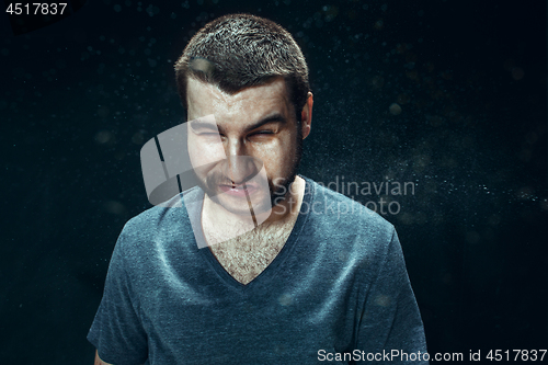 Image of Young handsome man with beard sneezing, studio portrait