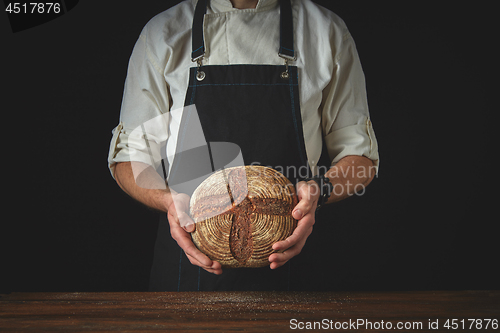 Image of fresh round bread male hands holding