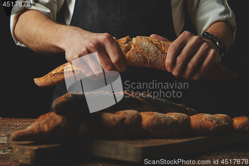 Image of Baker\'s hands break the baguette