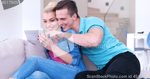 Image of couple relaxing at  home with tablet computers