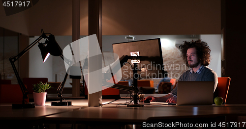 Image of man working on computer in dark office