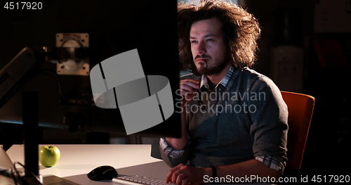 Image of man working on computer in dark office