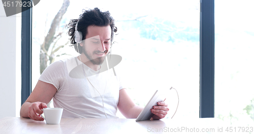 Image of young man listenig music on tablet at home