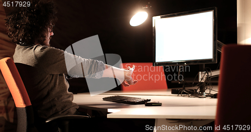 Image of man working on computer in dark office