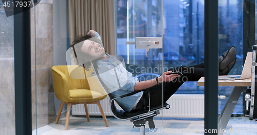 Image of businessman sitting with legs on desk