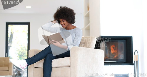 Image of black woman at home reading book