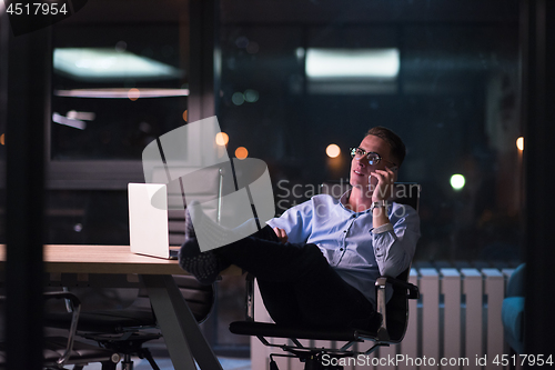 Image of businessman using mobile phone in dark office