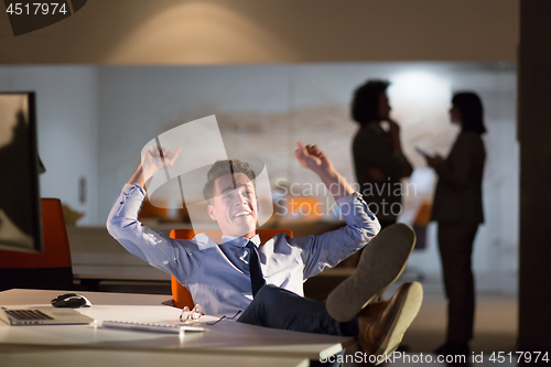 Image of businessman sitting with legs on desk at office