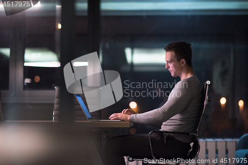 Image of man working on laptop in dark office