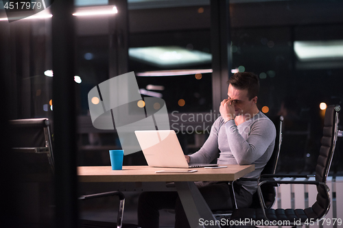 Image of man working on laptop in dark office