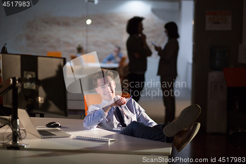 Image of businessman sitting with legs on desk at office