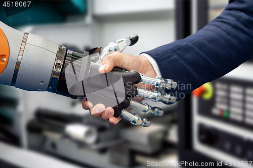 Image of Hand of a businessman shaking hands with a Android robot.