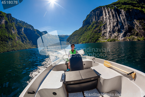 Image of Woman driving a motor boat Seven Sisters waterfall on the backgr