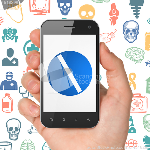 Image of Medicine concept: Hand Holding Smartphone with Pill on display