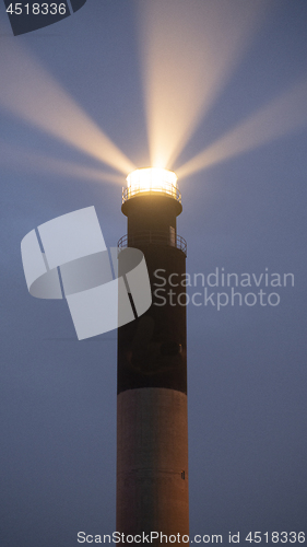 Image of Oak Island Lighthouse Beams into the Seafoam at Fort Caswell