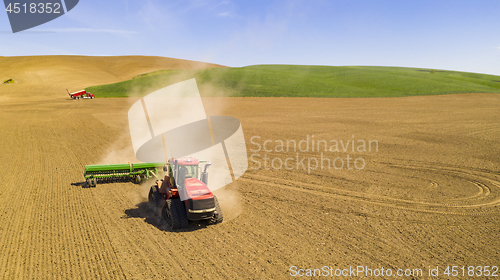 Image of Red Tractor tows the Plow in the agricultural farm field