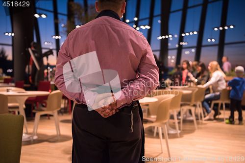 Image of waiter standing with hands behind his back