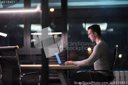 Image of man working on laptop in dark office