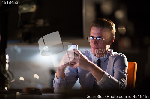 Image of man using mobile phone in dark office