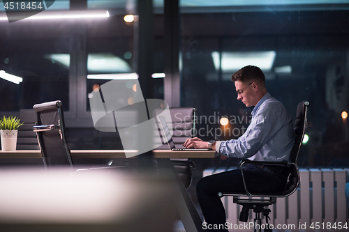 Image of man working on laptop in dark office