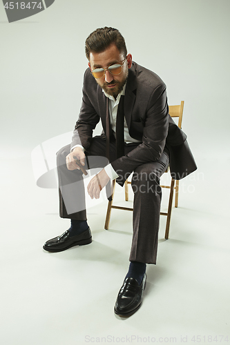 Image of The barded man in a suit holding cigar