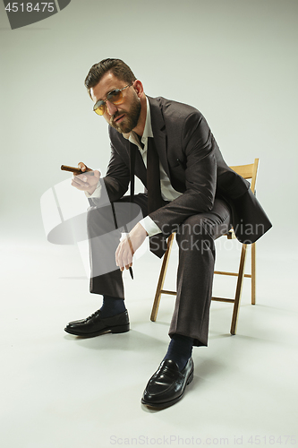 Image of The barded man in a suit holding cigar