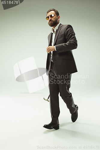 Image of The barded man in a suit holding cane.