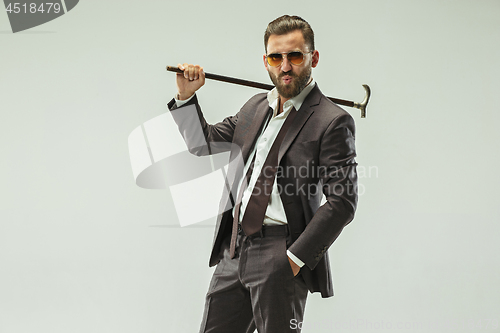 Image of The barded man in a suit holding cane.