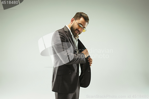 Image of The barded man in a suit holding leather purse