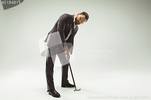 Image of The barded man in a suit holding cane.