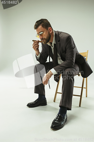 Image of The barded man in a suit holding cigar