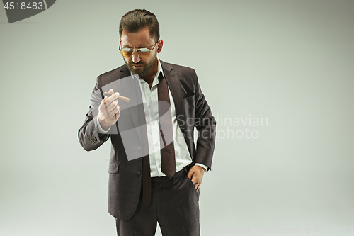 Image of The barded man in a suit holding cigar