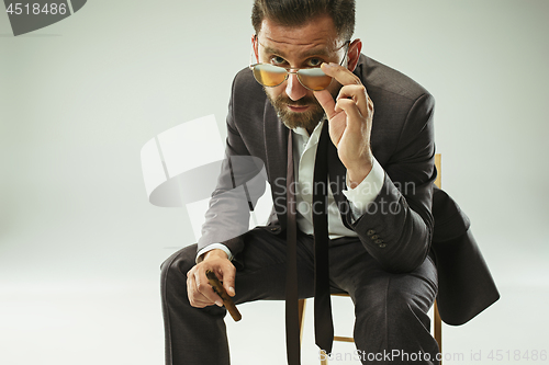 Image of The barded man in a suit holding cigar