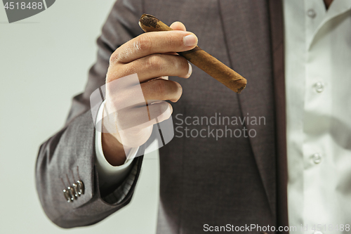 Image of The barded man in a suit holding cigar