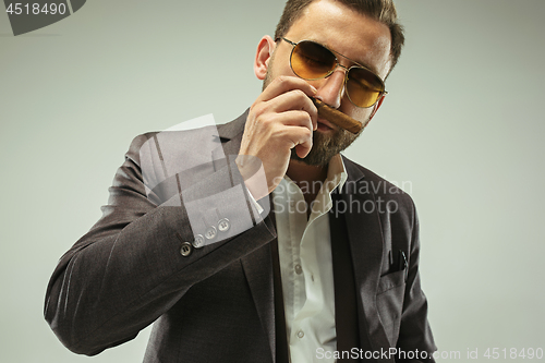 Image of The barded man in a suit holding cigar