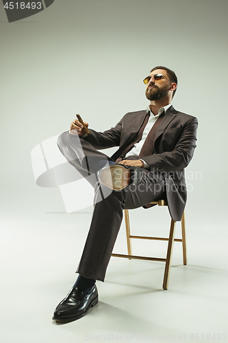 Image of The barded man in a suit holding cigar