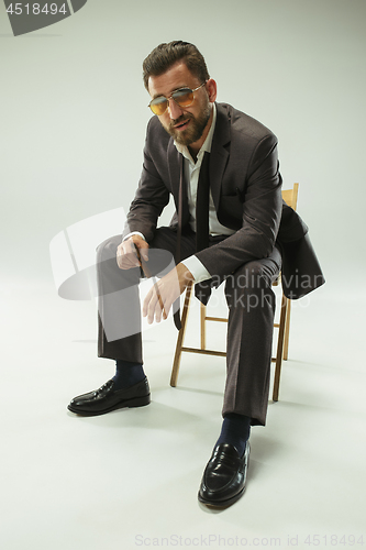 Image of The barded man in a suit holding cigar