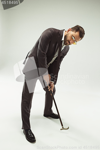 Image of The barded man in a suit holding cane.