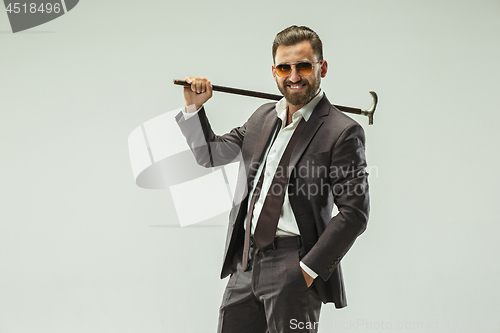 Image of The barded man in a suit holding cane.