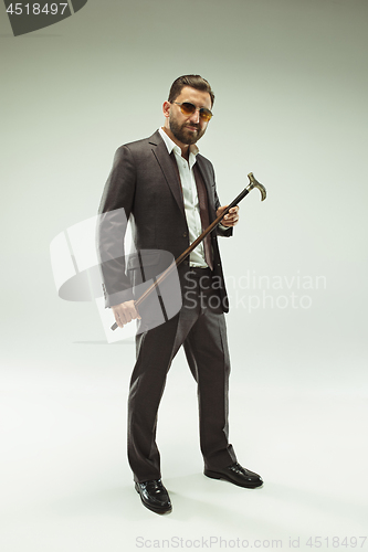 Image of The barded man in a suit holding cane.