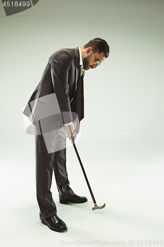 Image of The barded man in a suit holding cane.