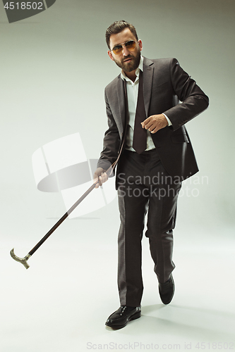 Image of The barded man in a suit holding cane.