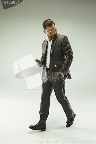 Image of The barded man in a suit holding leather purse