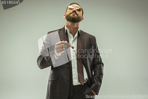 Image of The barded man in a suit holding cigar