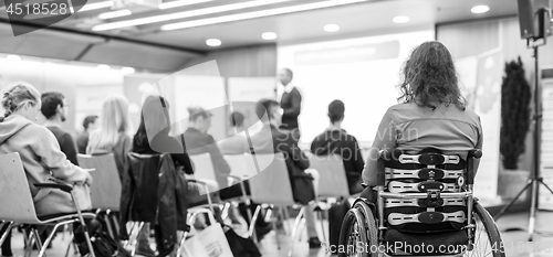 Image of Rear view of unrecognizable woman on a wheelchair participating at business conference talk.