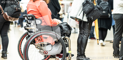 Image of Close up of unrecognizable hanicapped woman on a wheelchair queuing in line to perform everyday tasks.