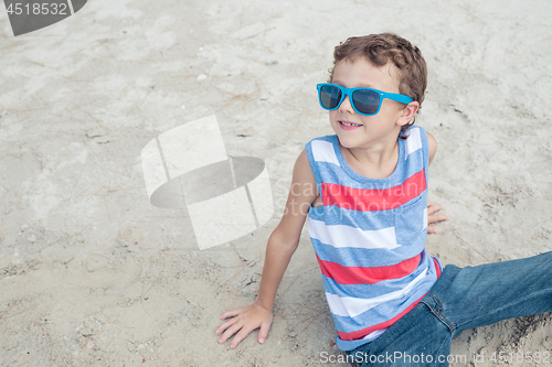 Image of One happy little boy playing on the beach at the day time.