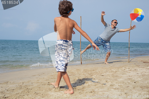 Image of Father and son playing football on the beach