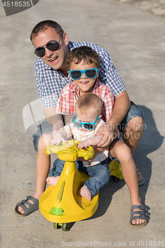 Image of Father and two sons playing on the road at the day time.